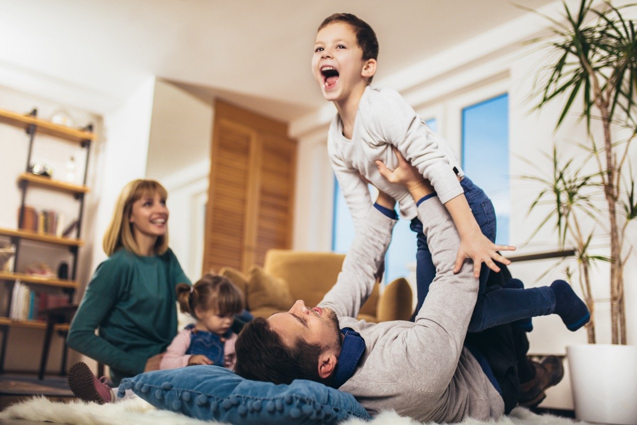 Happy family having fun on floor of in living room at home, laughing. Selective focus.